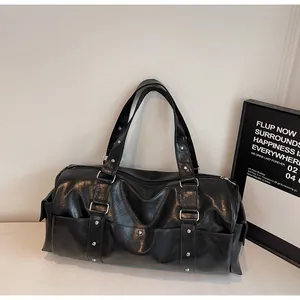 Detailed close-up of a black vintage duffel bag with silver studs and leather handles