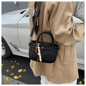 Detail view of a black leather handbag with chic colorful wooden bead charm and strap