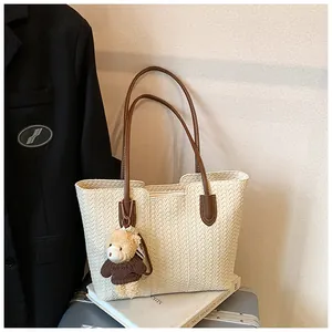 Close-up of cream woven tote bag with herringbone texture and brown leather handles