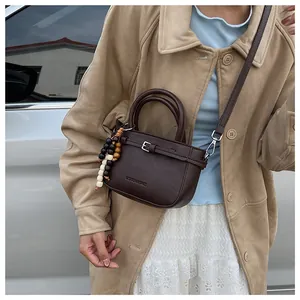 Detail of a vintage dark brown leather crossbody bag with wooden bead charm
