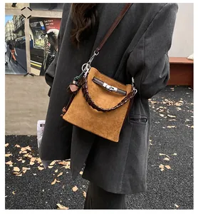 Detail of brown matte bucket bag with woven handle and metallic swivel lock