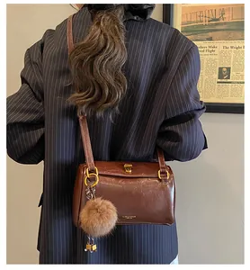Détail du sac cylindre rétro marron foncé en cuir ciré avec boucles dorées