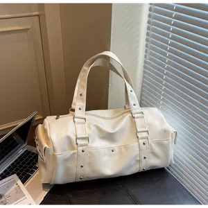 Detail of a creamy white leather travel tote with silver rivets in a stylish office setting