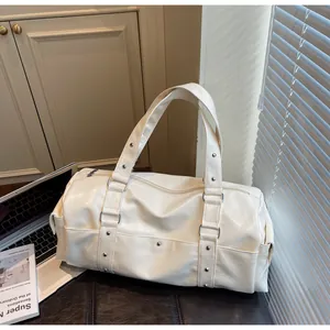 Detail of cream travel tote bag showing shiny PU leather with silver rivets and stitching
