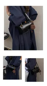 Détail du sac cylindrique noir avec fermoir doré rotatif et pendentif boule en peluche brune