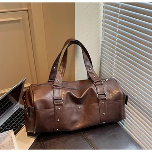 Detailed shot of a dark brown vintage PU leather travel bag with rivets on a leather bench