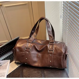 Detailed view of dark brown leather travel bag with silver studs and durable handles