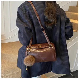 Sac cylindre vintage marron avec fermoir doré et porte-clés pompon sur un costume