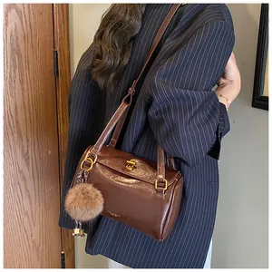 Détail du sac cylindrique marron vintage avec fermoir doré et pompon en peluche