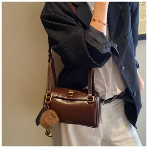 Détail du sac cylindre marron vintage avec fermoir doré et pendentif boule peluche