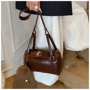 Détail du sac cylindre rétro marron foncé au fini brillant et fermoir rotatif doré