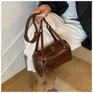 Détail du sac Boston cylindrique marron foncé avec fermoir doré et breloque pompon