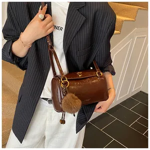 Détail d'un sac Boston cylindrique marron café avec garnitures dorées et pompon