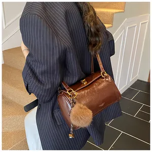 Détail du sac polochon marron avec fermoir doré et accessoire à pompon en fourrure