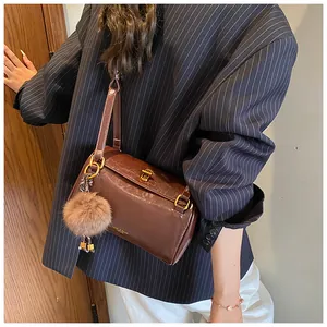 Détail du sac cylindre marron foncé avec texture cuir brillant et boucle en métal doré