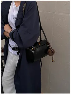 Détail du sac cylindrique en cuir noir avec ferrures dorées et breloque en peluche