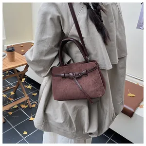 Detail einer dunkelbraunen Wildledertasche mit Lederriemen in warmer Herbstkulisse