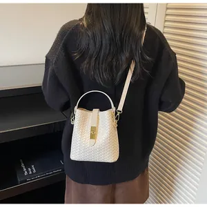 Detailed view of cream woven bucket bag texture with gold clasp and top handle