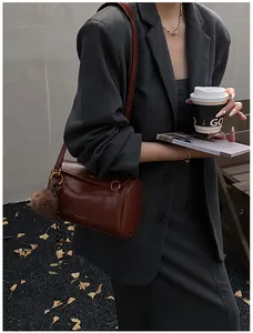 Sac cylindrique rétro marron foncé avec logo doré et détail de charme pompon en peluche