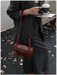Détail du sac cylindre marron vintage avec fermoir doré et pompon en peluche en ville