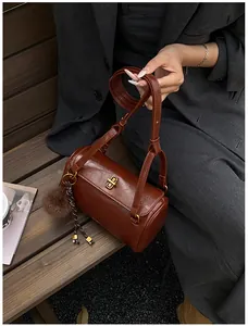 Détail du sac polochon marron avec fermoir doré et pendentif boule en peluche