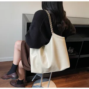 Close-up of the beige tote bag bottom featuring embossed logo and textured leather finish