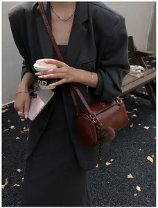 Détail du sac polochon marron foncé avec pompon en peluche et finitions dorées