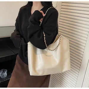 Close-up of cream leather tote bag featuring chain strap and embossed fashion logo