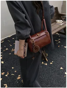 Détail du sac polochon marron avec fermoir tournant doré et pompon en peluche doux