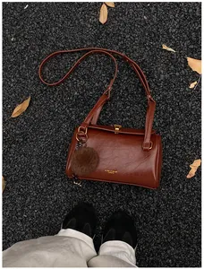 Détail d'un sac cylindrique marron vintage avec des ferrures dorées et texture en cuir