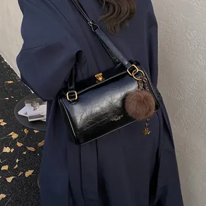 Sac cylindre noir brillant chic avec boucle dorée et pendentif pompon en peluche