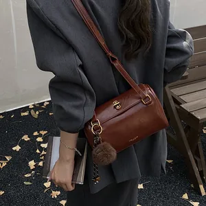Sac Boston en cuir marron vintage avec charm boule en peluche et garniture dorée