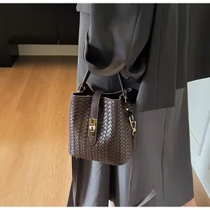 Detailed close-up of woven bucket bag featuring elegant gold metal twist lock and texture