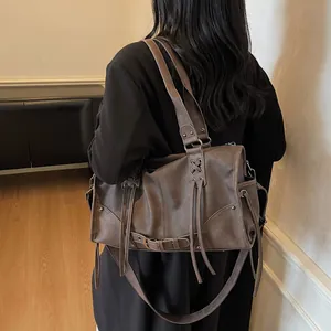 Borsa hobo marrone scuro retrò con frange e rivetti mostrata in un contesto di vita