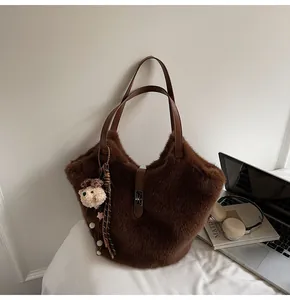 Détail du sac fourre-tout marron en peluche avec bretelles en cuir et charme d'ours