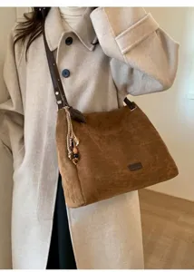 Detail of brown faux suede tote bag with woven beaded tassel and leather shoulder strap