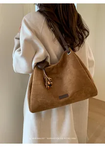 Detail of suede hobo bag with heart pendant and wooden beads on adjustable strap