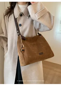 Close-up of brown suede tote bag with leather straps and decorative beaded tassel charm