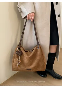 Brown suede tote bag with heart charm and ethnic tassel detail shown on model