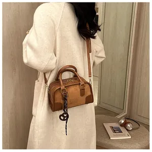 Détail du sac Boston en cuir marron avec gaufrage de marque et breloque en cœur