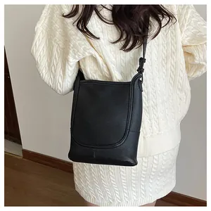 Détail du sac seau noir grainé porté par un mannequin en tenue de tricot doux