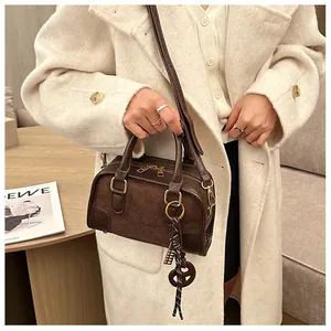 Gros plan sur un sac Boston marron avec détails de chaîne et fermeture éclair dorée