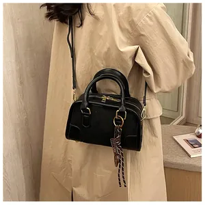Sac à main Boston noir chic avec détails dorés présenté dans un décor lifestyle