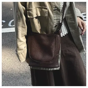 Vue détaillée du sac bandoulière en cuir grainé marron avec surpiqûres courbées iconiques