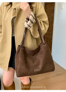Detail of suede tote bag with leather strap and FASHION & BAG logo in dark brown color