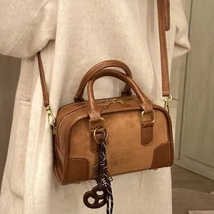 Sac Boston marron avec chaîne dorée et cuir texturé porté par un mannequin