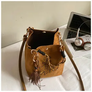 Detailansicht der braunen Wildleder-Beuteltasche mit schwarzen Schleifen und Quasten