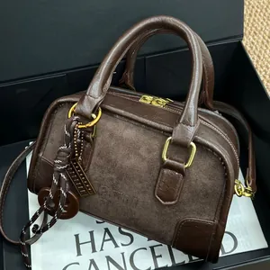 Sac Boston en cuir marron foncé avec chaîne dorée et corde tressée dans un coffret cadeau