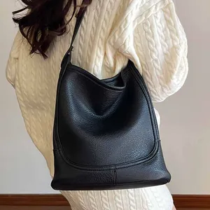 Grand sac cabas noir en cuir grainé avec bandoulière réglable porté à l'épaule