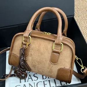 Sac Boston en cuir marron avec chaîne dorée et daim présenté dans sa boîte de luxe